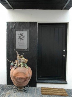 Une entrée de maison avec une porte noire et une décoration en ardoise